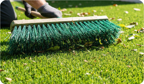 brossage du gazon synthétique pour redresser les fibres et enlever les débris